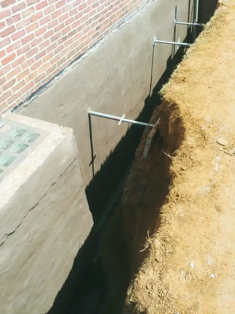 Afgewerkte curatieve kelderdichting langs de buitenzijde van een woning met waterdichte buitenafdichting.