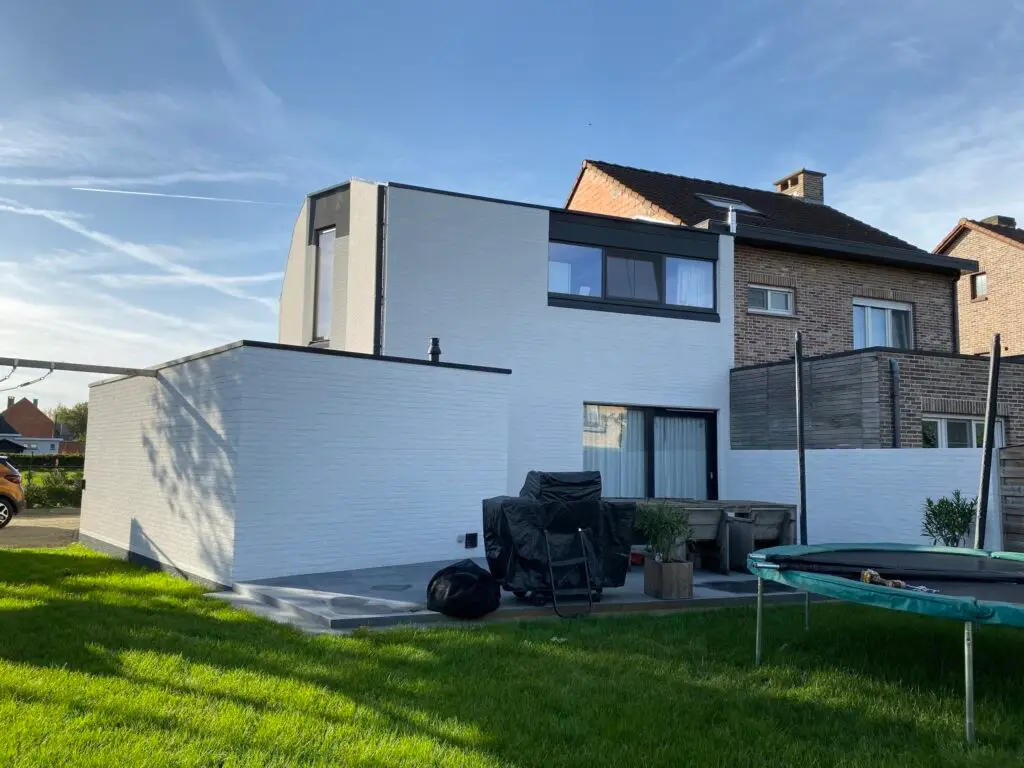 Woning afgewerkt met witte spuitkurk waarbij de oorspronkelijke gevelstructuur behouden bleef.